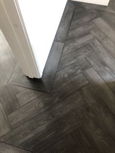 a white refrigerator sitting in the corner of a room next to a wooden flooring