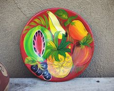 a plate with fruit painted on it next to a wall