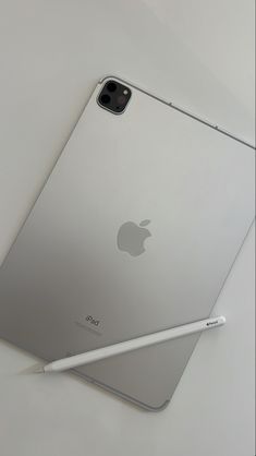 an ipad with a pen on top of it next to the back of its case