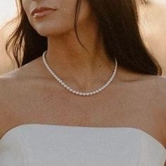 a woman in a white dress wearing a necklace