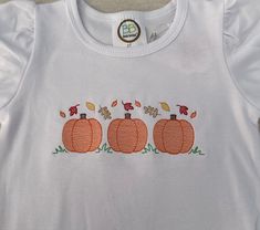 three pumpkins embroidered on a white shirt