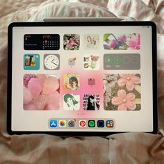 an open laptop computer sitting on top of a bed covered in pink and white sheets