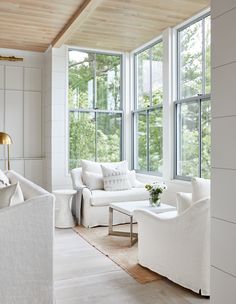 a living room filled with white furniture and large windows