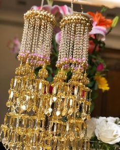 two golden chandeliers with pink and white flowers in the background