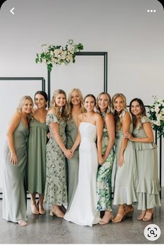 a group of women standing next to each other in front of a wall with flowers