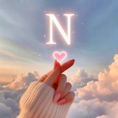 a hand holding up a heart in the sky with the letter n above it and clouds below