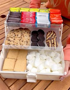 a child holding a plastic container filled with cookies and marshmallows