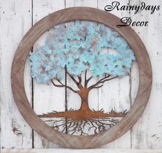 a metal tree with blue leaves in a circular frame on a white wooden wall hanging