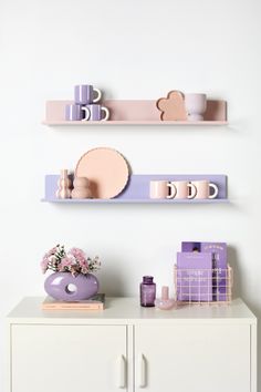 two shelves with pink and purple items on them, one shelf has plates and cups