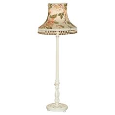 a lamp that is sitting on top of a white stand with a flowered shade