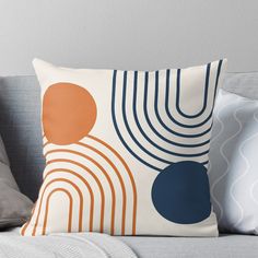 an orange and blue throw pillow sitting on top of a gray couch next to pillows