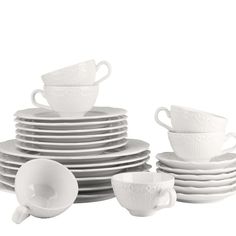 a stack of white cups and saucers sitting next to each other on top of plates