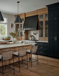 a large kitchen with wooden floors and black cabinetry on the walls, along with an island in the middle