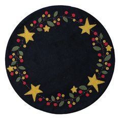 a black round rug with stars and berries on the front, surrounded by green leaves