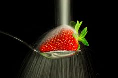 a strawberries on a spoon being sprinkled with water