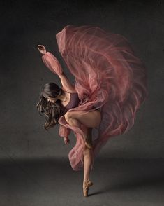 a woman in a pink dress is dancing with her arms spread out and legs bent