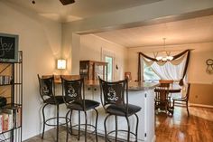 three bar stools sit in front of a kitchen island with bookshelves on it