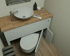 a white toilet sitting next to a wooden counter top under a bathroom mirror and sink