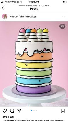 a multicolored cake with white frosting and fruit on top