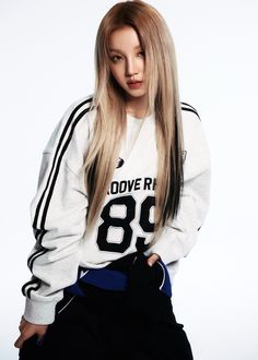 a woman with long blonde hair wearing a white sweatshirt and black sweatpants, posing for the camera