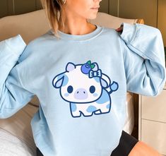 PLEASE NOTE:  This is a UNISEX sweater.  If you want an oversized look then consider ordering up a size. This cute blueberry cow sweater will look adorable on you!  Makes for a great kawaii gift for your loved ones as well. The collar is ribbed knit, so it retains its shape even after washing. There are no itchy side seams on these sweaters.  .: 50% cotton, 50% polyester .: Medium-heavy fabric (8.0 oz/yd² (271.25 g/m .: Loose fit .: Sewn-in label .: Runs true to size Oversized Kawaii Sweatshirt With Cartoon Print, Oversized Kawaii Cartoon Print Sweatshirt, Cute Blue Sweatshirt With Graphic Print, Cute Oversized Blue Tops, Blue Long Sleeve Kawaii Sweatshirt, Blueberry Clothes, Blueberry Outfit, Cow Merch, Blue Clothes Aesthetic