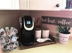 a coffee maker sitting on top of a wooden tray next to cups and mugs