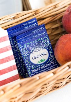 two bags of organic breakfast tea sit in a basket next to peaches and an american flag