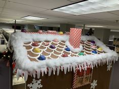 a gingerbread house with icing on the roof and decorations hanging from the roof