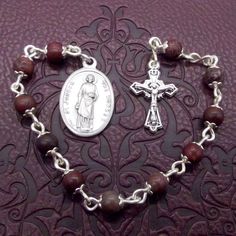 Apache Jasper Single Decade Rosary This is a beautiful handmade Apache Jasper single decade rosary bead set. It has an intricate Crucifix at one end and a lovely Saint Joseph the Worker Medal at the other. Saint Joseph was given the noble task of caring and watching over the Virgin Mary and Jesus by God. St Joseph taught his carpentry trade to the young Jesus before He went to begin His ministry of preaching and healing. By working, mankind participates in the creative work of God by being produ Handmade Spiritual Rosary With Oval Beads, Spiritual Rosary Bracelet For Jewelry Making, Hail Mary, Mary And Jesus, St Joseph, Rosary Beads, Patron Saints, Jasper Beads, Bead Caps