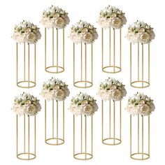 six gold metal flower stands with white flowers on each side and one in the middle