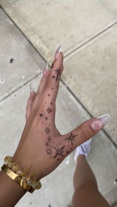 a woman's hand with stars and snowflakes tattooed on her left arm