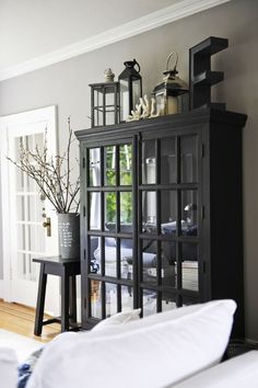 a black cabinet with glass doors and vases on top