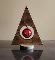 a wooden triangle with a red ornament in it's center on a table