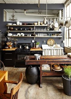 a kitchen filled with lots of pots and pans on top of shelves next to a table