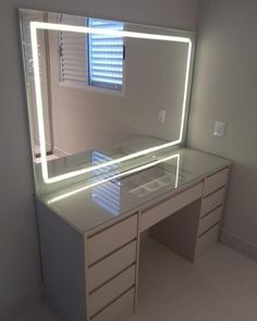 a white desk with a lighted mirror and drawers