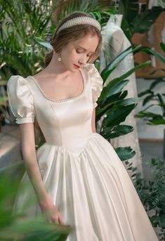 a woman in a white dress standing next to plants