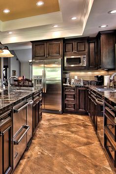 a large kitchen with granite counter tops and stainless steel appliances, along with dark wood cabinets