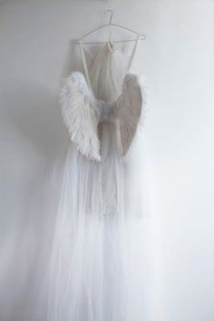 a white dress with angel wings hanging on a wall