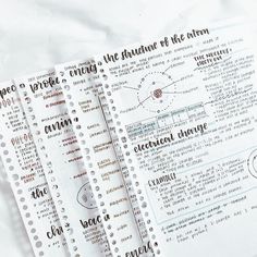 three notebooks sitting on top of each other next to some paper with writing on them