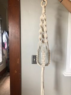 a person is holding up a macrame hanging from a hook on the wall