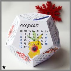 an origami calendar cube with flowers on it and the date august written in english