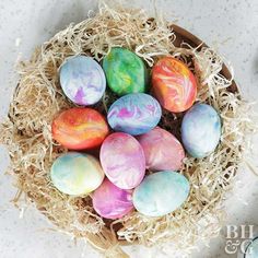 a basket filled with dyed eggs sitting on top of a table