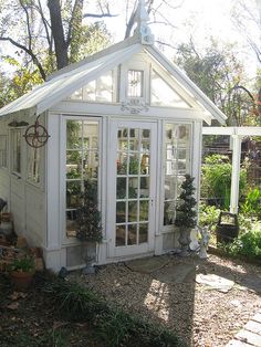 a small white house sitting in the middle of a garden