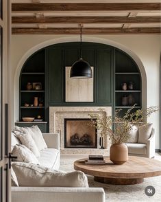 a living room filled with furniture and a fire place in front of a fireplace covered in bookshelves