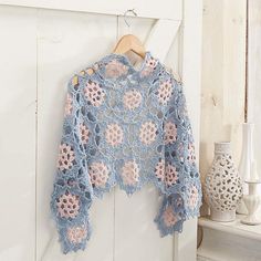 a crocheted sweater hanging on a white door