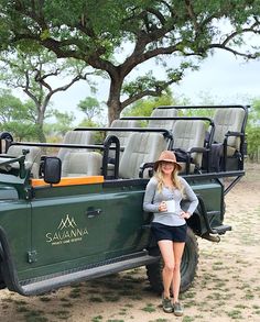 a woman standing in front of a green truck with seats on the roof and back