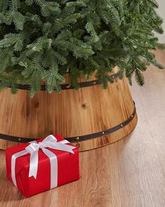 a christmas tree in a wooden bucket with a red gift box on the floor next to it