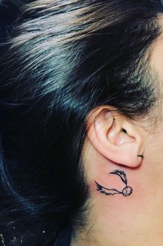 a close up of a person's ear with a bird tattoo on her left side