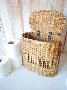 a wicker basket with two rolls of toilet paper next to it