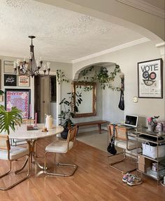 a living room filled with lots of furniture and a dining table surrounded by plants on top of hard wood flooring